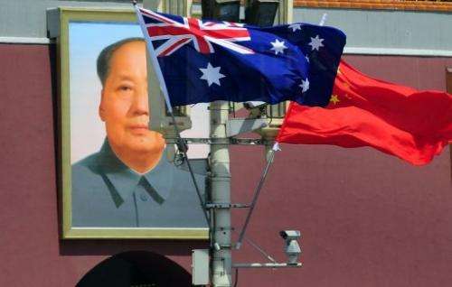 The national flags of Australia and China are displayed before a portrait of Mao Zedong in Beijing in April 2011