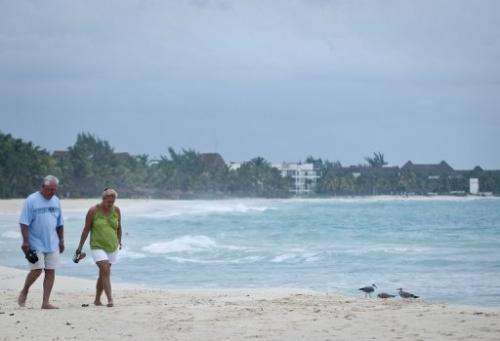 Tourists walk along the beach of Playa del Carmen, near Cancun in Mexico, on October 27, 2011