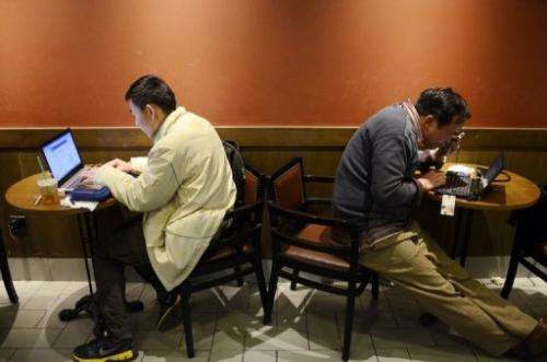 Two men browse the internet on their laptops at a cafe in Beijing on November 2, 2012