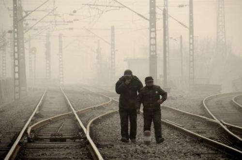 Two men walk along a railway line during smoggy weather in Beijing on January 12, 2013