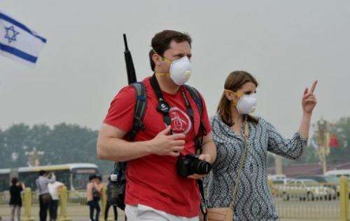 Two tourists wear face masks as they visit Tiananmen Square on a heavily polluted day in Beijing on May 8, 2013