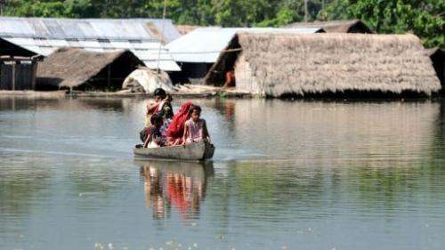 Villagers paddle their boat near submerged houses in a village near Kaziranga National Park on September 27, 2012