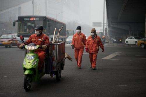 Workers wearing facemasks cross a road during heavily polluted weather in Beijing on January 29, 2013