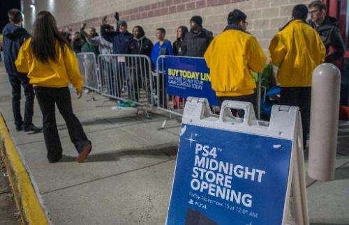 Yellow-clad customer service representatives brief camped-out shoppers as they wait in line to purchase the new PlayStation 4 (P