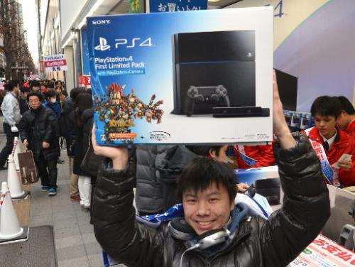 A customer holds up a Sony PlayStation 4 video game console after buying it in Tokyo on February 22, 2014