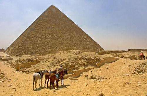 A horseman waits with his horses for tourists in front of Egypt's Cheops Pyramid at Giza plateau south of Cairo 13 June 2002