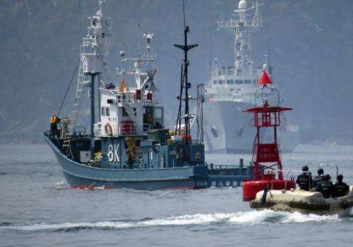 A Japanese whaling ship (L) leaves Ayukawa port in Ishinomaki City on April 26, 2014 under under tight security by the Japan Coa