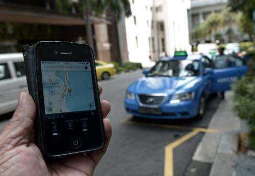 A man shows the Uber app on a smartphone on October 10, 2014