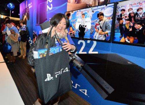 A woman carries a newly-purchased Sony PlayStation 4 video game console at the Sony building in the Ginza district of Tokyo on F