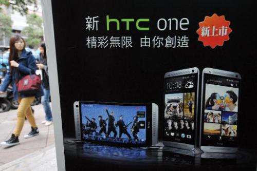 A woman walks past HTC advertising in Taipei on May 2, 2013