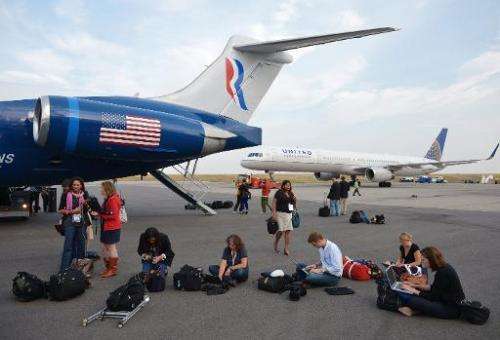 Journalists work on laptops next to Mitt Romney's campaign plane, at Denver International Airport, on September 23, 2012