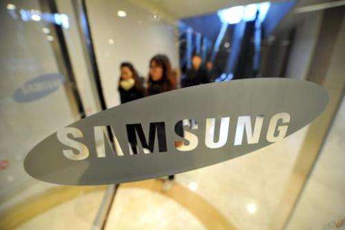 Pedestrians walk past a logo of Samsung Electronics at the company's headquarters in Seoul on January 24, 2014