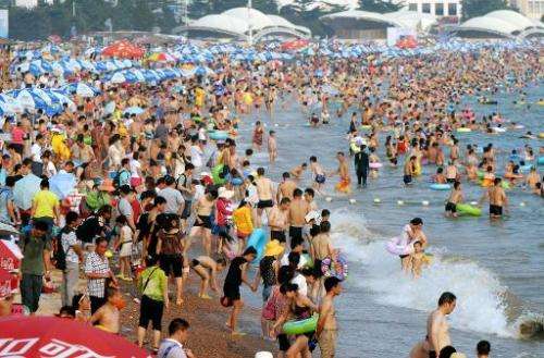 People gather to cool off on a beach in Qingdao, in eastern Shandong province, as a record-setting summer heat wave hit much of 
