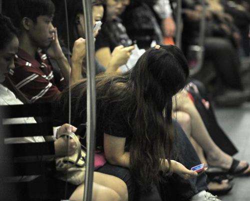 People use their smartphones while travelling on a Mass Rapid Transit train in Singapore, on April 30, 2014