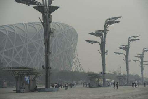People walk near the 'Birds Nest' national stadium in Beijing amid heavy smog on October 10, 2014