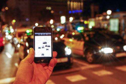 The Uber app is seen on a smartphone as taxis drive on the Paseo de Gracia in Barcelona, Spain, on December 9, 2014