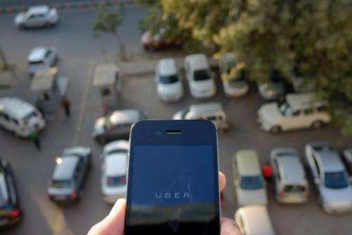 The Uber smartphone app, used by customers to book taxis using its service, is pictured over a parking lot in the Indian capital