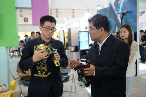 This picture taken on May 14, 2014 shows visitors playing with robots during the 17th China Beijing International High-Tech Expo