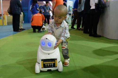 This picture taken on May 14, 2014 shows a child looking at a domestic robot during the 17th China Beijing International High-Te