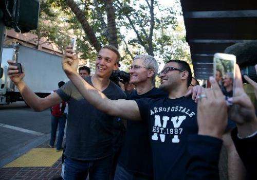 Apple CEO Tim Cook (C) takes a selfie photo with people waiting in line to buy the new iPhone 6 at an Apple Store on September 1