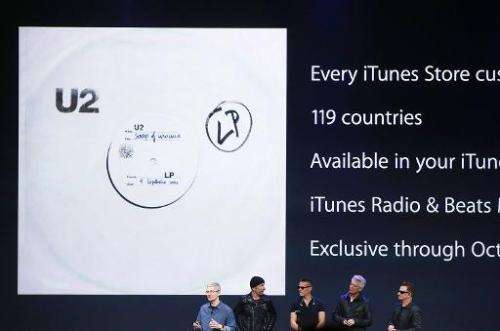 Apple CEO Tim Cook (L) announces the free download of the new U2 album on iTunes as members of U2 look on in Cupertino, Californ