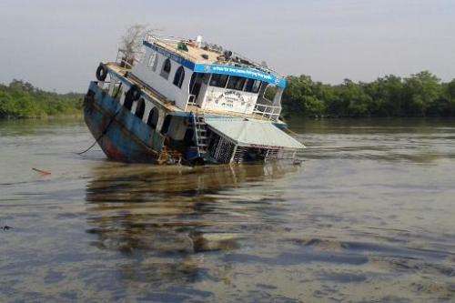 A Bangladeshi oil-tanker lies half-submerged on the Shela River in the Sundarbans in Mongla on December 9, 2014 after it was hit
