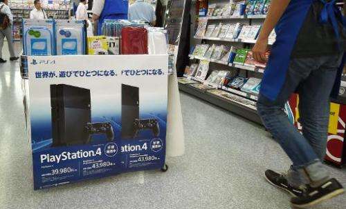 A customer walks past Sony's PlayStation 4 consoles at an electronics store in Tokyo on August 13, 2014