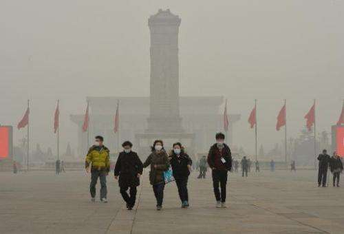 Chinese tourists wearing facemasks during a visit to Tiananmen Square as heavy air pollution continues to shroud Beijing, on Feb