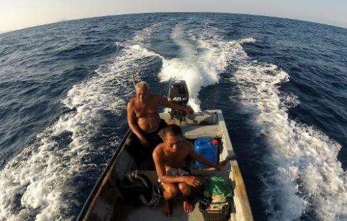 Fish listener Harun Muhammad (L) mans his fishing boat at sea near Setiu lagoons with his son Zuraini on June 8, 2014