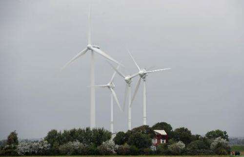 Wind turbines stand next to a house near Husum, northern Germany on September 20, 2010