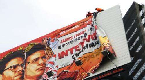 Workers remove the poster for &quot;The Interview&quot; from a billboard in Hollywood, California, on December 18, 2014