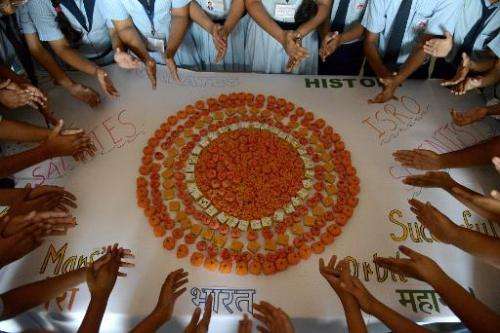 Schoolchildren in Ahmedabad mark the success of India's Mars Orbiter Mission by creating a planet Mars using orange-coloured swe