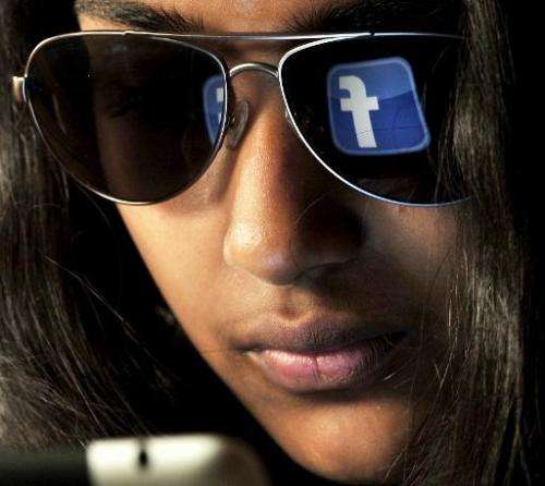 The 'Facebook' logo is reflected in a young Indian woman's sunglasses as she browses on a tablet in Bangalore on May 15, 2012. A