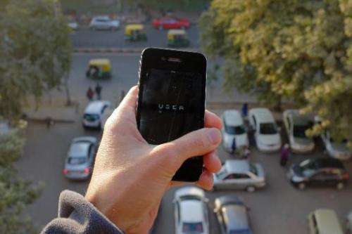The Uber smartphone app, used to book taxis using its service, is pictured over a parking lot in the Indian capital New Delhi on