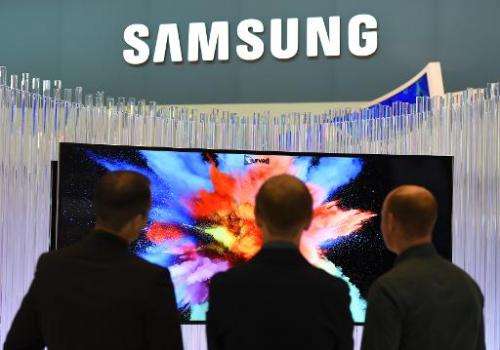 Visitors look at a curved TV set, displayed at the booth of South Korean electronic giant Samsung, during the consumer electroni