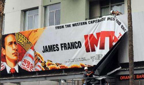 Workers remove a poster for The Interview from a billboard in Hollywood on December 18, 2014