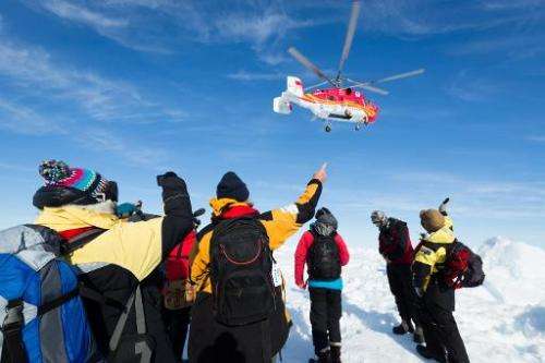 A helicopter from the nearby Chinese icebreaker Xue Long hovers above passengers from the Russian ship MV Akademik Shokalskiy as