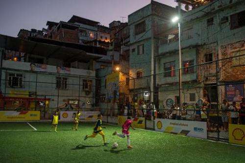 Children play football after the inauguration of the new technology pitch at Mineira favela in Rio de Janeiro, on September 10, 