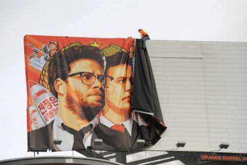 Workers remove a poster-banner for &quot;The Interview&quot; from a billboard in Hollywood, California, December 18, 2014