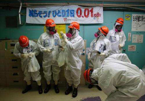 Members of the media and Tokyo Electric Power Co employees inside the number five reactor building at the crippled  Fukushima Da