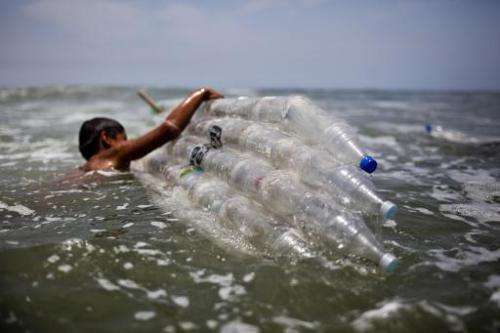 A boy gets into the sea with a surfboard made from plastic bottles as part of an environmental recyclying project, in Lima, on F