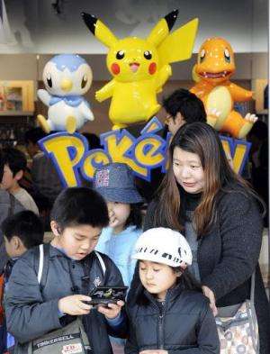 A boy plays Nintendo's portable video game 'DS' in front of display of game character Pokemon, at a shop in Tokyo, on April 4, 2