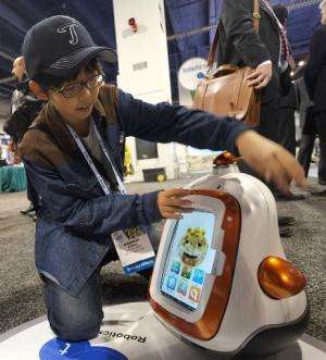 A boy plays with a robot presented  by Future Robots  during the 2014 International CES at the Las Vegas Convention Center on Ja