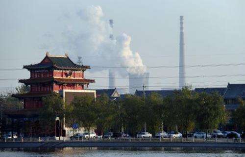 A building newly built in the architecture of imperial China stands near the cooling towers and smokestack chimneys of a coal-fi