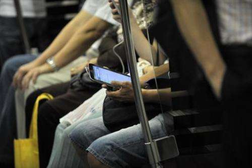 A commuter is seen using his smartphone while travelling on a Mass Rapid Transit train in Singapore, on April 30, 2014