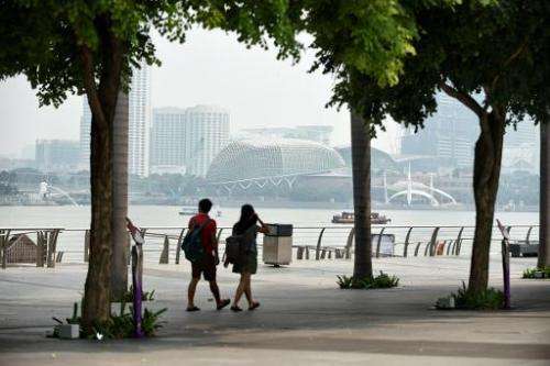 A couple walks along the promenade as haze can be seen blanketing Esplanade theatre in Singapore on September 15, 2014