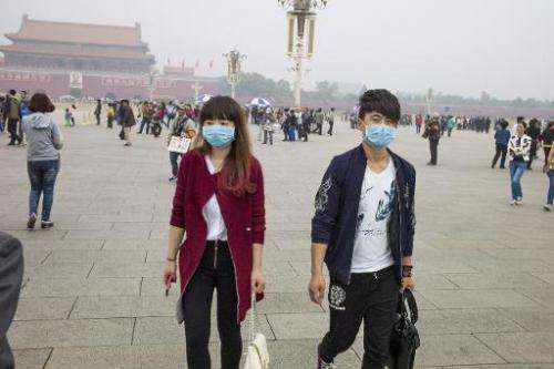 A couple wear face masks as they walk on Tiananmen Square in Beijing on October 11, 2014 after days of heavy smog