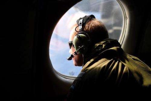 A crew member looks out an observation window aboard a Royal New Zealand Air Force (RNZAF) P3 Orion maritime search aircraft as 