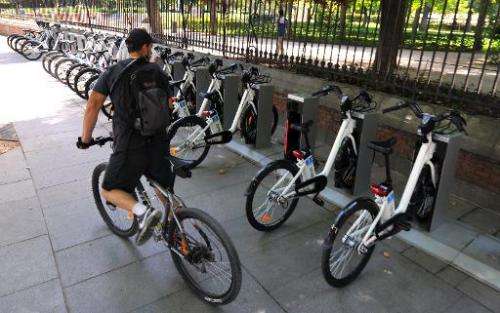A cyclist looks at electric bicycles parked at a bike-sharing station in Madrid on June 23, 2014