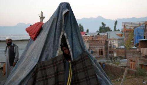 A displaced woman sits in a makeshift tent in Srinagar on September 16, 2014 following heavy floods